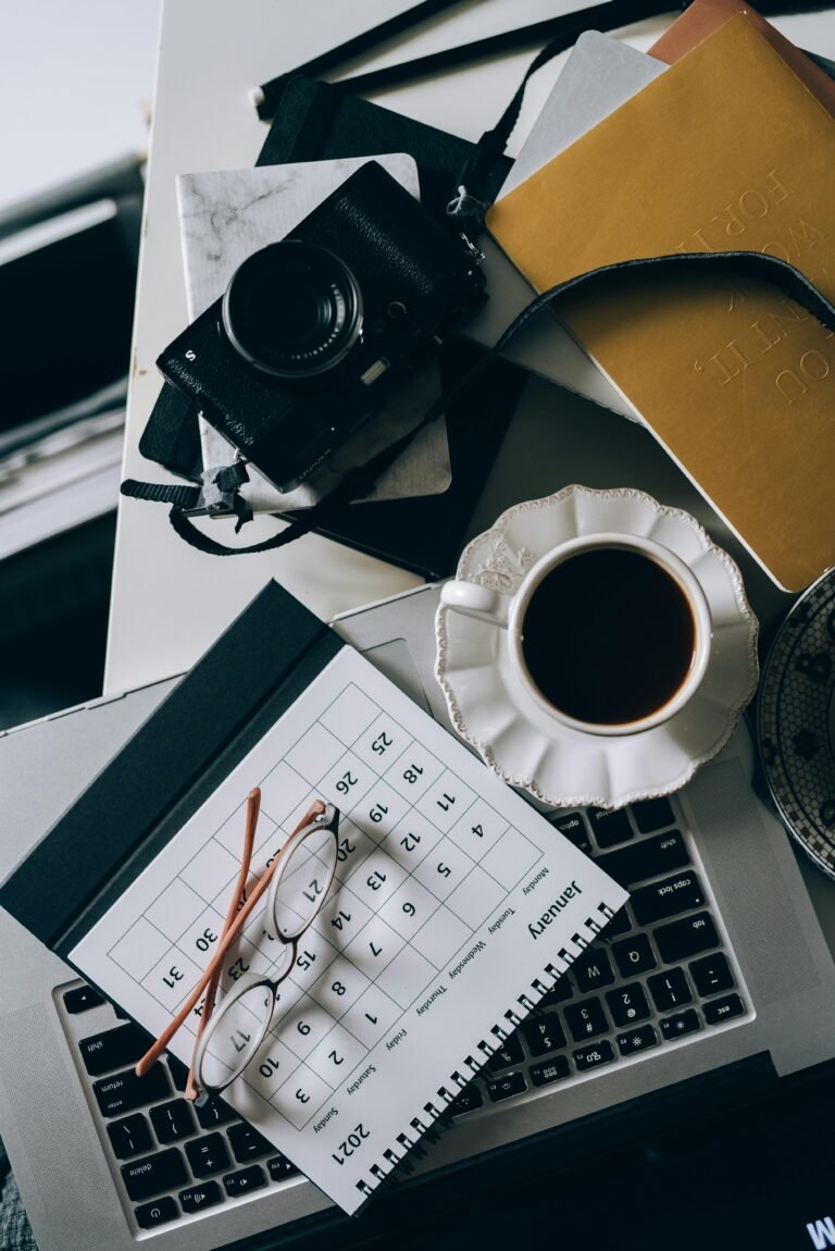 Flat lay of a modern workspace with camera, coffee, and calendar for creative inspiration.