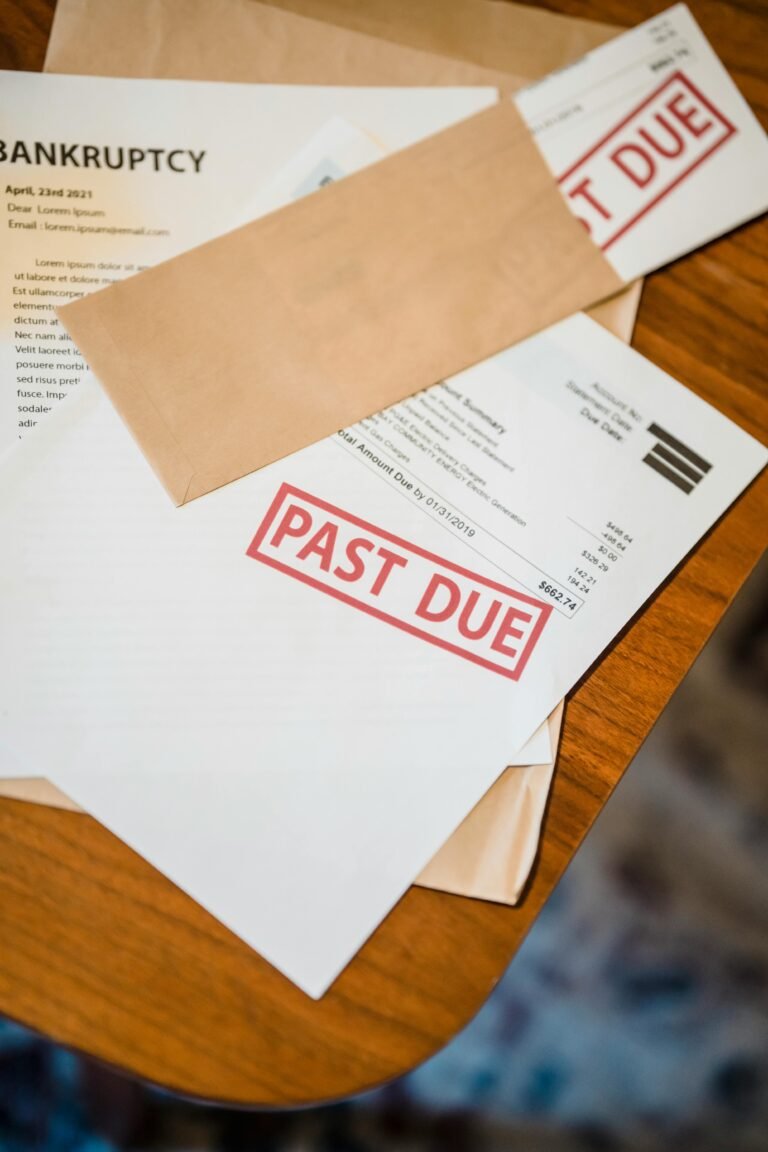 Photograph showing past due and bankruptcy documents on a wooden table.